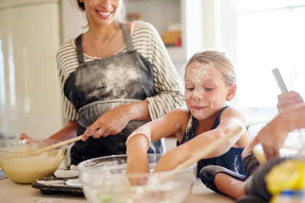 Een storm aan het bakken. Foto van twee kleine meisjes bakken met hun moeder in de keuken. — Stockfoto