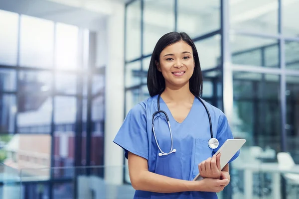 Jouw gezondheid is mijn prioriteit. Portret van een jonge vrouwelijke arts die een digitale tablet vasthoudt terwijl hij in een ziekenhuis staat. — Stockfoto