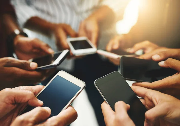 É mais fácil fazê-lo digitalmente. Foto de perto de um grupo de empresários irreconhecíveis usando seus celulares em sincronia. — Fotografia de Stock