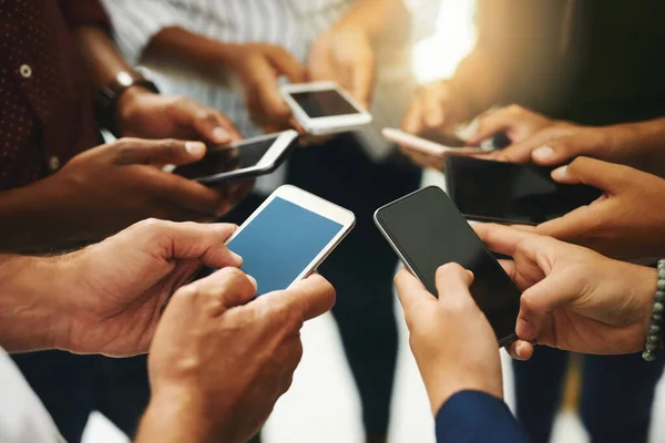 Mantendo sua conexão de equipe bem sucedida. Foto de perto de um grupo de empresários irreconhecíveis usando seus celulares em sincronia. — Fotografia de Stock