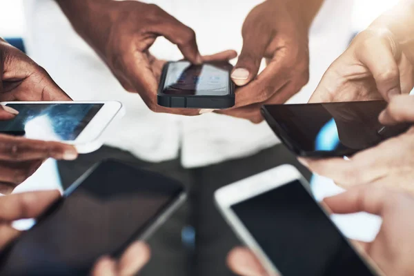 Conectando online e em tempo real. Tiro recortado de um grupo de pessoas usando seus telefones inteligentes em sincronia. — Fotografia de Stock