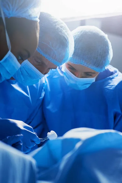 Centrado en el procedimiento. Toma de un grupo de cirujanos trabajando en un paciente en un quirófano. — Foto de Stock