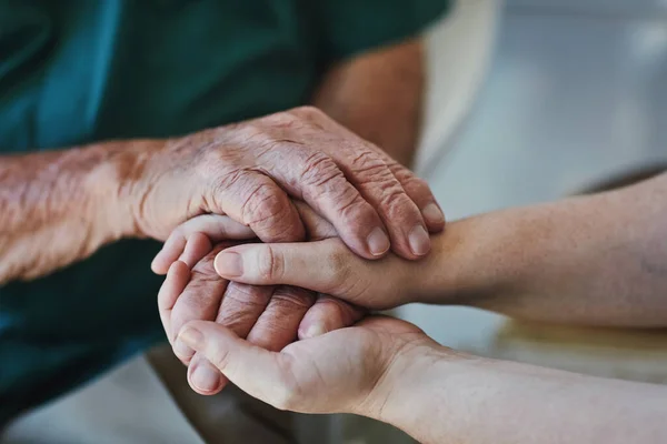 Too often we underestimate the power of a listening ear. Closeup shot of a woman holding a senior mans hands in comfort. — Stock Photo, Image