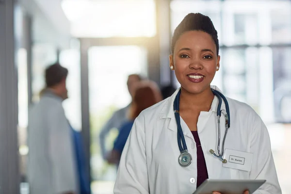 La atención médica de calidad es de suma importancia para mí. Retrato de una joven doctora de pie en un hospital con sus colegas de fondo. — Foto de Stock