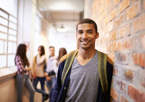 Los amigos se burlan de la universidad. Retrato de un joven y guapo estudiante apoyado en una pared con sus amigos de fondo. — Foto de Stock