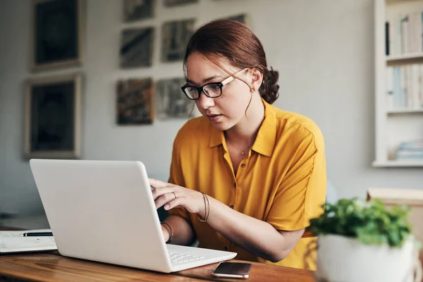 Pon tu mente en ello para lograrlo. Fotografía de una mujer joven usando un ordenador portátil mientras trabajaba desde casa. — Foto de Stock