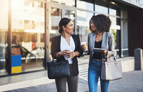 The main topic of talk is always success. Shot of two businesswomen having a discussion while walking in the city.