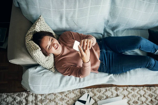 Trabajo fuera, fin de semana fuera. Fotografía de una mujer joven usando un teléfono inteligente mientras se relaja en casa. — Foto de Stock