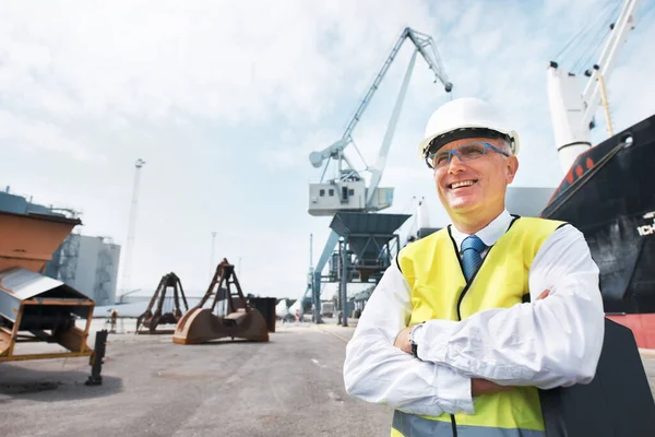 Vivo para mi trabajo. Un trabajador portuario parado en el puerto en medio de la actividad de la industria naviera. — Foto de Stock