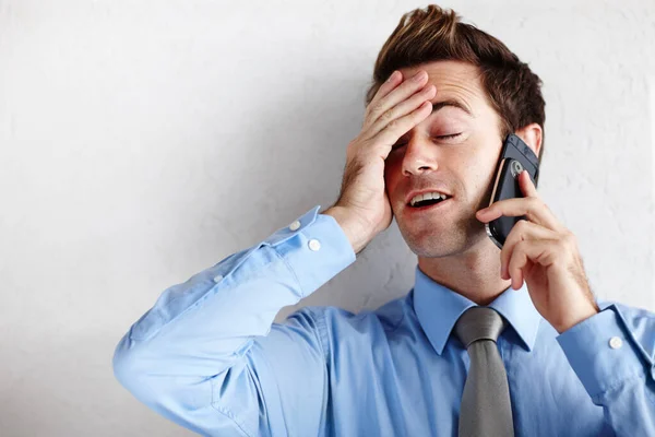 Volle opluchting na de promotie. Een opgeluchte jonge zakenman wrijft zijn gezicht terwijl hij een telefoontje aanneemt. — Stockfoto