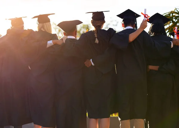 Došli jsme spolu tak daleko. Zadní snímek skupiny vysokoškolských studentů, kteří spolu stojí v den promoce. — Stock fotografie