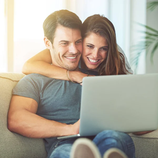 Relajarse junto con un poco de entretenimiento en línea. Foto de una pareja joven y cariñosa usando un portátil en casa. —  Fotos de Stock