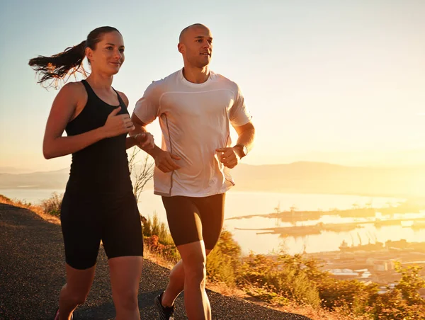 Running is part of their daily routine. Shot of a young couple running together along a road. — Stock Photo, Image