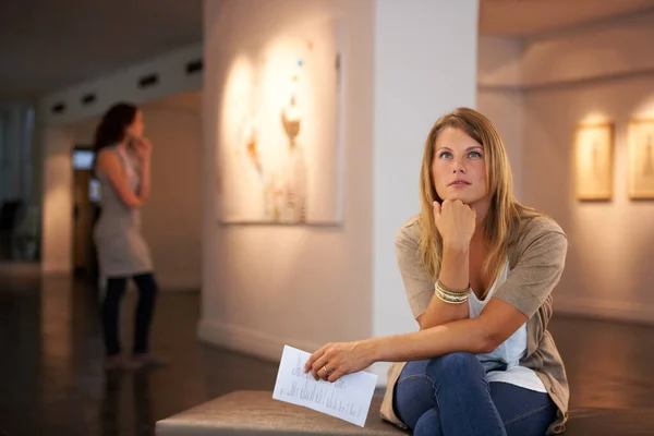Reflexionando sobre los temas de las pinturas. Dos jóvenes amigos mirando pinturas mientras asisten a una exposición. — Foto de Stock