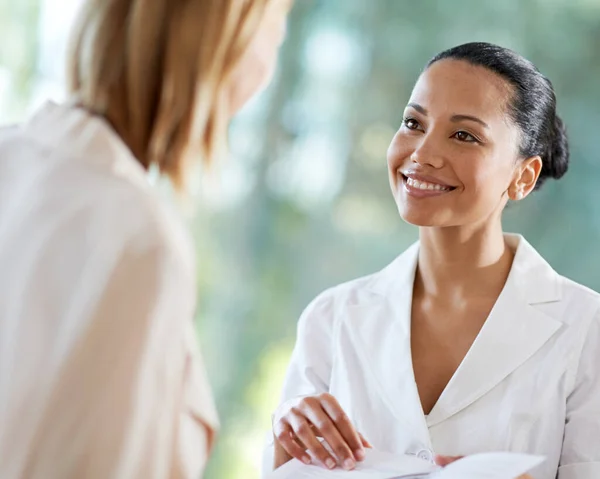 Stolt över att bara kunna erbjuda det bästa inom kundvård. Skjuten av en ung kvinna checkar in vid receptionen. — Stockfoto