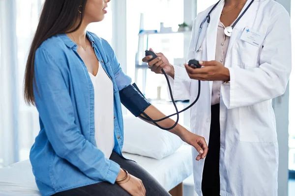 Bloeddruk zegt veel over je gezondheid. Schot van een jonge vrouw die haar bloeddruk liet meten tijdens een controle bij een arts. — Stockfoto