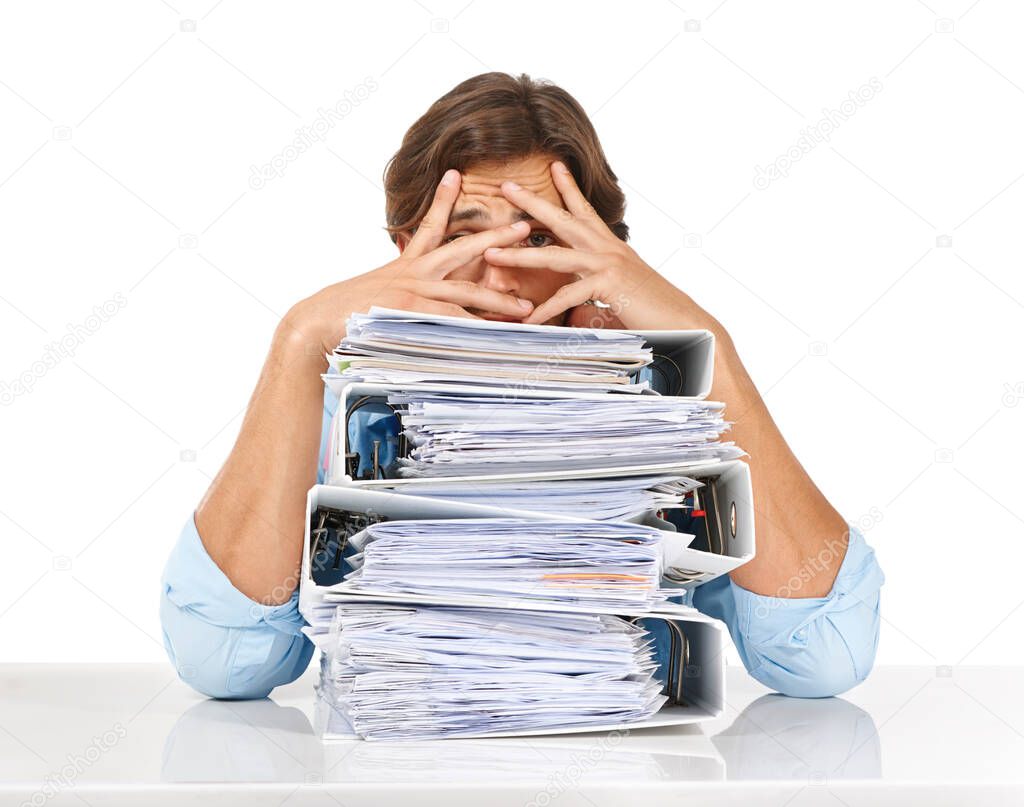 The paperwork just keeps piling up. Studio shot of a businessman sitting with a pile of files and looking demotivated against a white background.