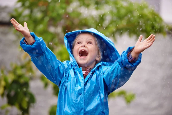 To enjoy the rainbow, first enjoy the rain. Shot of a young girl playing outside in the rain.