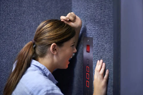 Ik zit hier vast. Schot van een angstige vrouw schreeuwend in een lift intercom. — Stockfoto