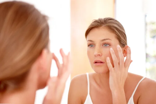 Cuidando su piel. Una mujer naturalmente hermosa aplicando crema hidratante en un espejo. — Foto de Stock
