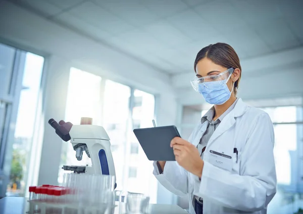 Het makkelijker maken om haar bevindingen aan de wereld bekend te maken. Foto van een vrouwelijke wetenschapper met behulp van een digitale tablet in een lab. — Stockfoto