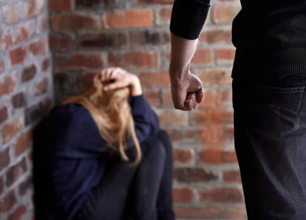 Der Versuch, sich zu verstecken. Misshandelte junge Frau mit den Händen im Haar, als ihr Täter vor ihr steht. — Stockfoto