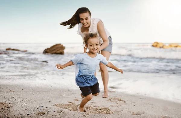 ビーチでのすべての楽しさとゲーム。ビーチで彼女の小さな息子との母親の絆のショット. — ストック写真