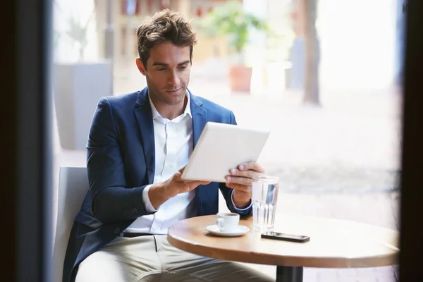 Tar igen kaffepausen. Skjuten av en ung affärsman njuter av en kopp kaffe när du använder en digital tablett. — Stockfoto