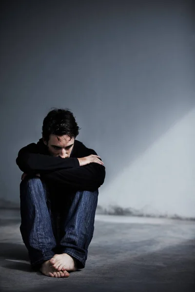 Radzenie sobie ze stresem emocjonalnym. Młody mężczyzna wygląda na zmartwionego siedząc boso na ziemi.. — Zdjęcie stockowe