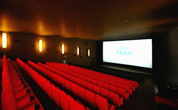 Světla, kamera, akce. Prázdné kino nebo kino s velkou obrazovkou a řadami červených sedadel. — Stock fotografie