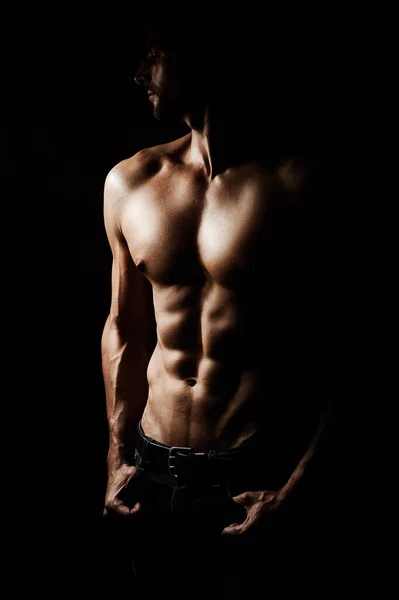 Esculpido a la perfección. Imagen discreta de un joven musculoso sobre un fondo negro. — Foto de Stock