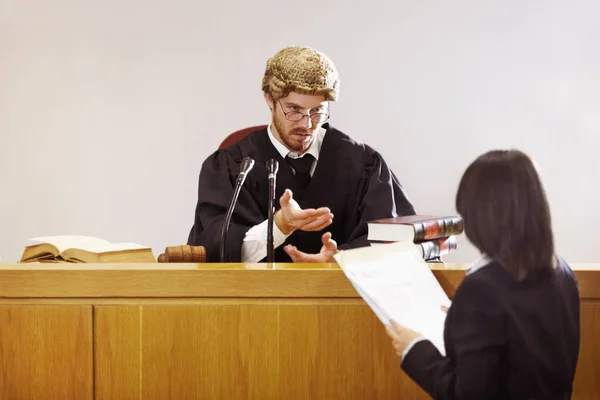 Представьте ваше дело... серьезный молодой судья, сидящий в зале суда со строгим выражением лица. — стоковое фото