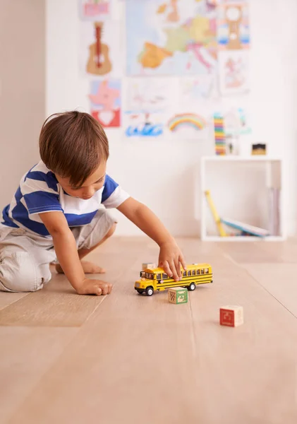 Las ruedas del autobús giran y giran. Shot of a cute little boy playing with his toys in his room. — Foto de Stock