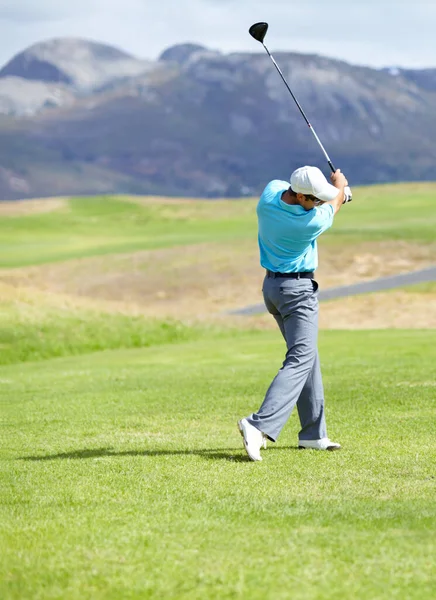 Driving it down the fairway. A young, fit male golfer following through after driving his ball down the fairway. — Stock Photo, Image