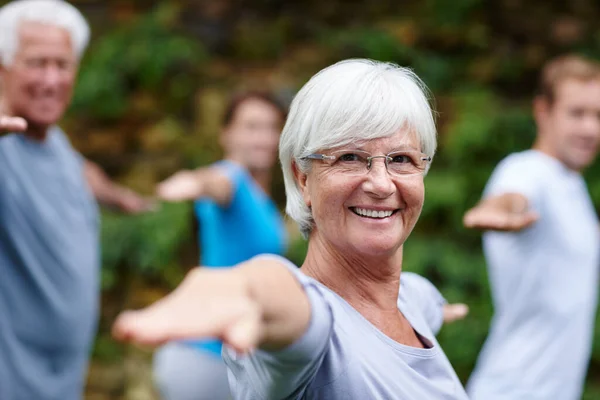 El yoga me lleva a mi lugar feliz. Toma de una mujer mayor haciendo yoga con otras personas al aire libre. —  Fotos de Stock