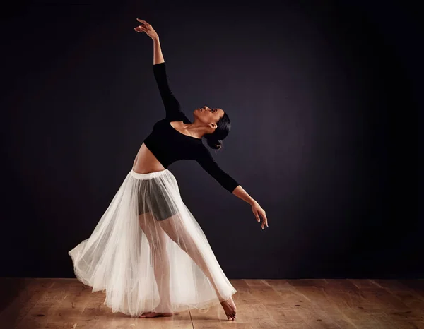 Олицетворение элегантности. Современная молодая танцовщица с мягкой белой юбкой для драматического эффекта. — стоковое фото