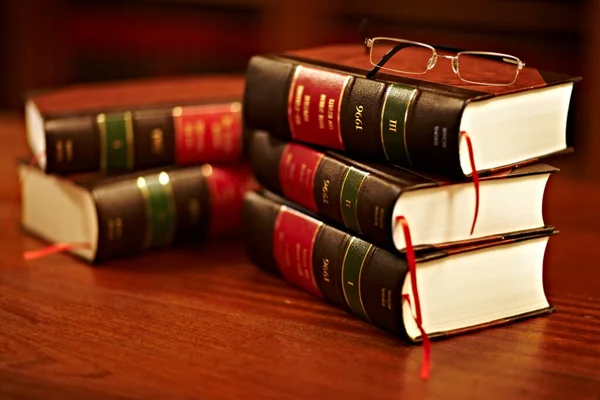 Leer je rechten kennen. Shot van een stapel juridische boeken en een paar glazen op een tafel in een studie. — Stockfoto
