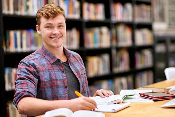 Er ist der Beste seiner Klasse. Porträt eines männlichen Studenten, der an einem Tisch in einer Universitätsbibliothek studiert. — Stockfoto