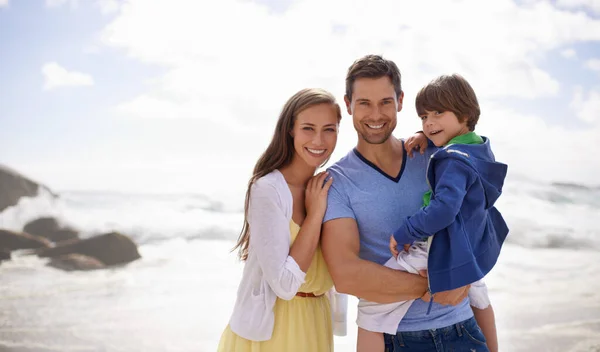 Счастливые дни, наполненные солнцем. Портрет счастливой семьи, стоящей вместе на пляже. — стоковое фото