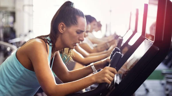 In de rij voor een gezonder leven. Gesneden foto van een groep jongeren die aan het trainen zijn op elliptische machines in de sportschool. — Stockfoto