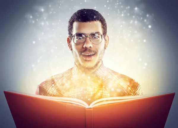 Околдован его скрытыми историями. Обрезанный снимок молодого человека, читающего книгу со светящимися страницами. — стоковое фото