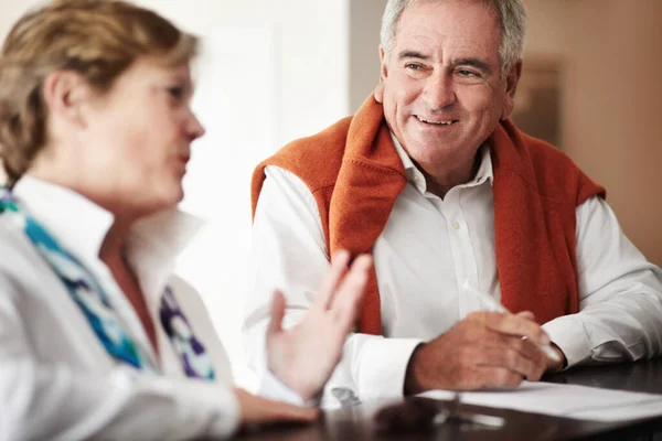 Disfrutando de una conversación en la recepción. Un hombre mayor y su esposa llenando formularios en la recepción de un hotel. — Foto de Stock