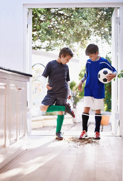 Pojkar kommer att vara pojkar. Skjuten av två pojkar som tar in smuts i huset efter fotbollsträning. — Stockfoto