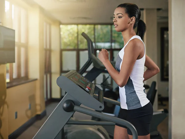 Sweating it out on the treadmill. Shot of a young woman exercising on a treadmill at the gym. — Stock Photo, Image
