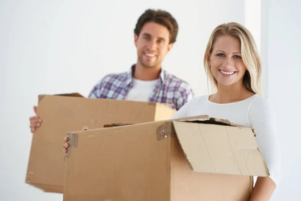 Klaar om nieuwe herinneringen te maken in hun eerste huis. Portret van een gelukkig koppel met bruine kartonnen dozen in hun nieuwe huis. — Stockfoto