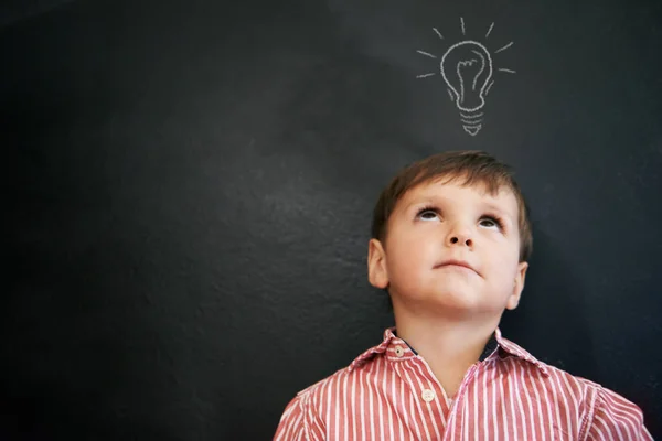 Hes got a lot of ideas. Studio shot of a young boy with a chalk-drawing light bulb above his head. — Stock Photo, Image