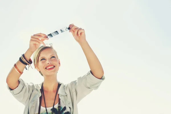 La vida es como la fotografía, se usan los negativos para desarrollarse. Una hermosa joven en un estudio sosteniendo una tira de negativos. — Foto de Stock