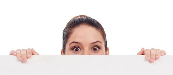 Dá para acreditar nisto? Estúdio tiro de uma jovem mulher espreitando sobre um cartaz banco isolado em branco. — Fotografia de Stock