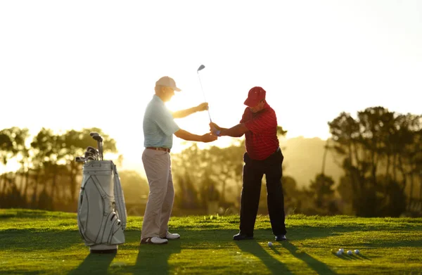 Trzymaj poziom klubowy przez huśtawkę. Mężczyzna golfista otrzymuje pomoc od swojego pomocnika na polu golfowym. — Zdjęcie stockowe