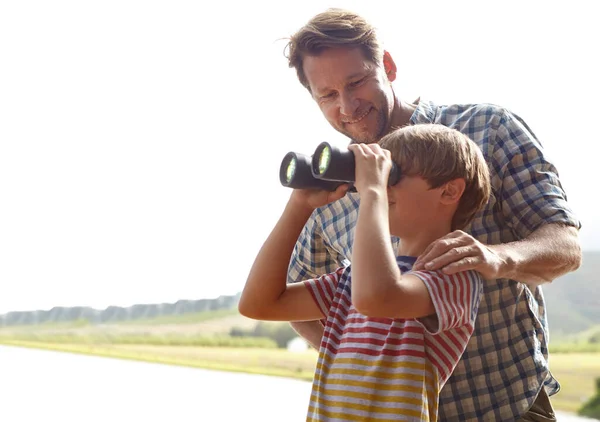 Looking out at the lake. Shot of a young boy and his father bird-watching nearby a lake. — Stock Photo, Image